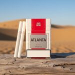 บุหรี่ Atlanta Red Premium ซองสีขาวแถบแดง พร้อมมวนบุหรี่วางบนขอนไม้ในทะเลทราย